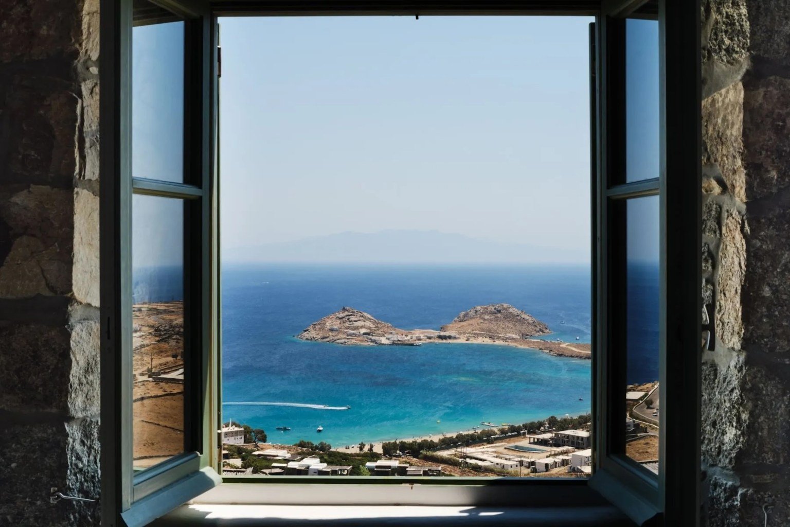 window in Mykonos home overlooking the water and an island